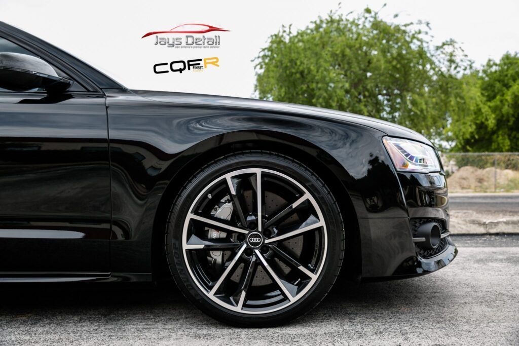 Black car with black and silver rims parked on asphalt.