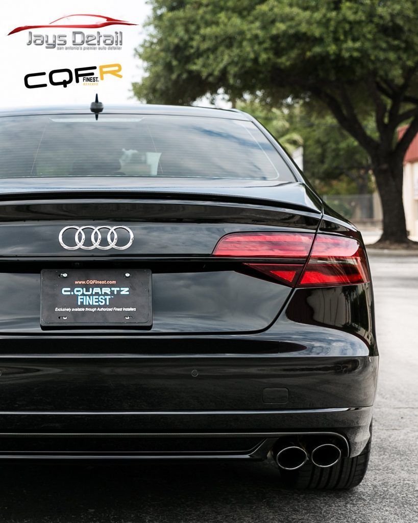 Black Audi sedan rear view with exhaust pipes, detailing logo and license plate.