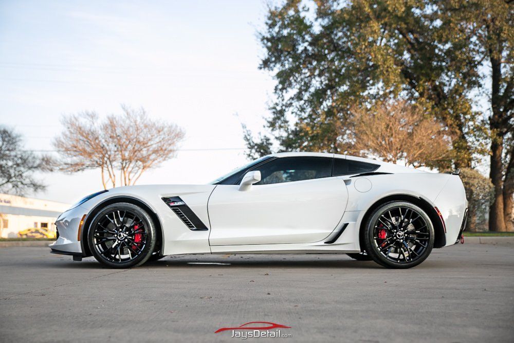 White Corvette sports car with black rims, parked on a street.