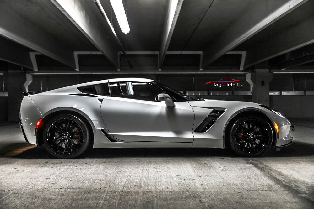 White sports car parked in an underground garage with black wheels and trim.