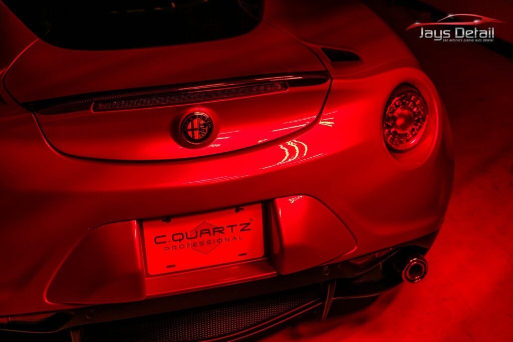 Red-lit close-up of a silver sports car's rear, license plate