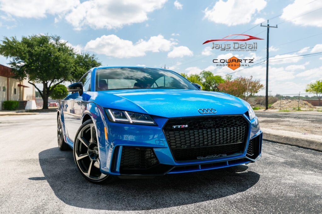 Blue Audi TT RS sports car parked on asphalt, sunny day.