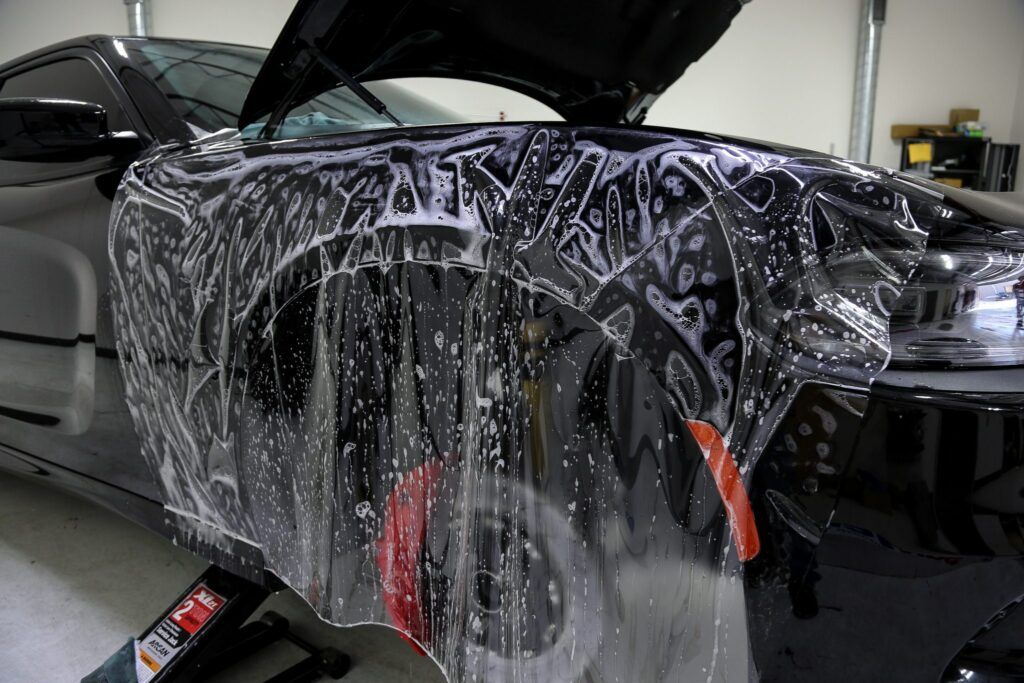 Black car being wrapped with protective film.