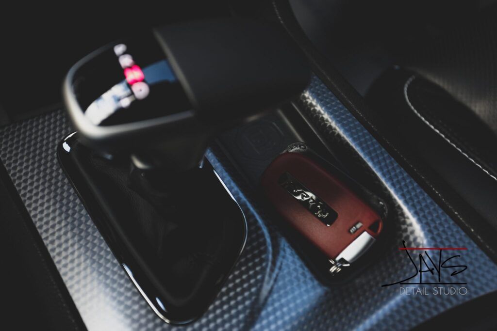 Car's interior, gear shift and car key visible. The key is red, lying in a storage compartment.
