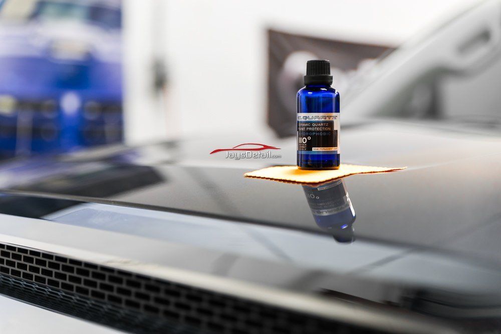 Blue car detailing product bottle on car hood.