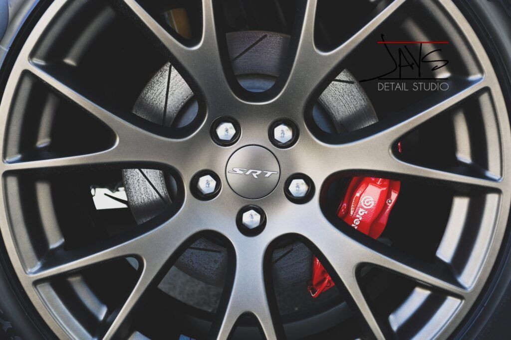 Close-up of a car wheel with a red brake caliper, gray spokes, and a black tire.