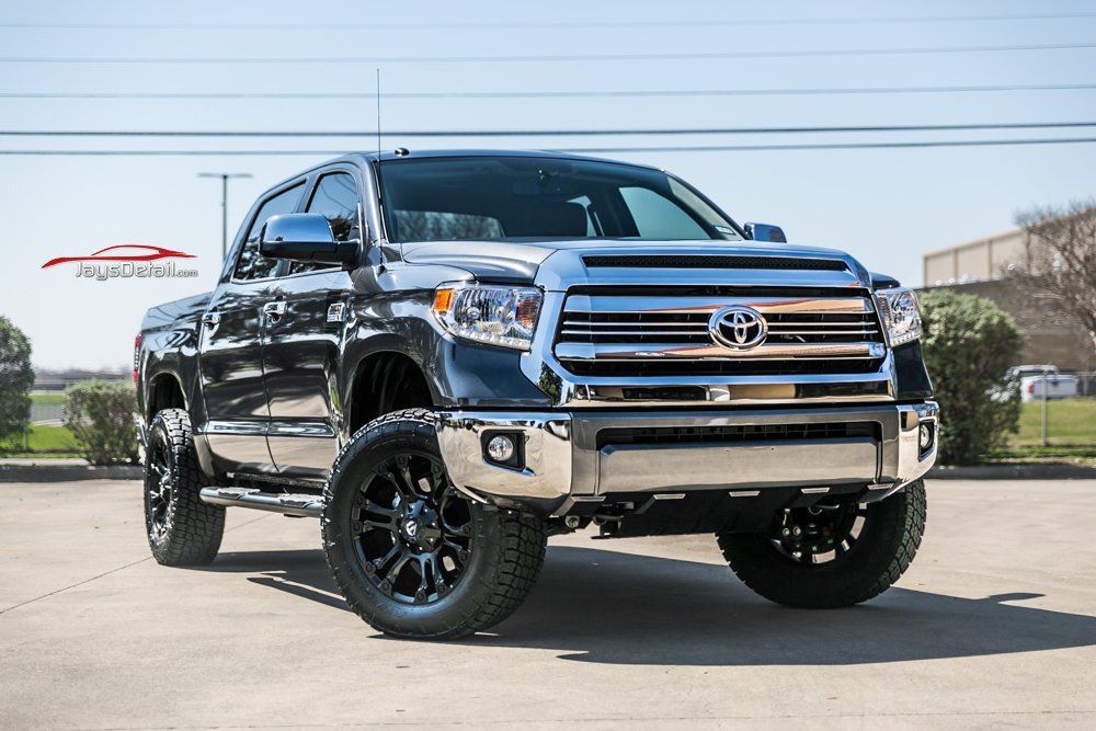 Black Toyota Tundra pickup truck with chrome accents and black wheels parked outdoors on a sunny day.