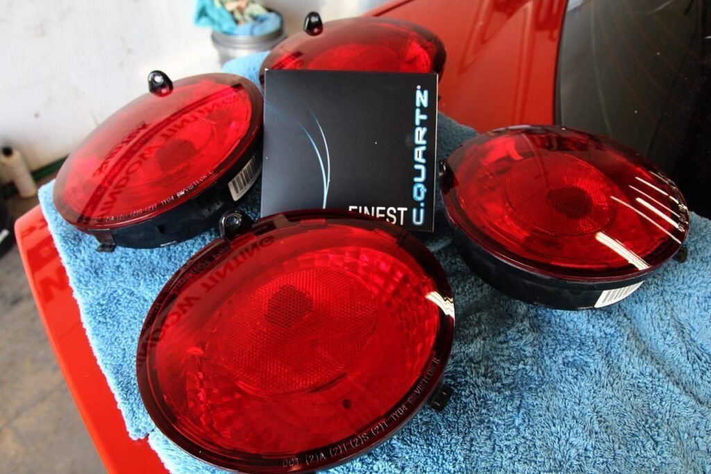 Four red car tail lights on a blue towel, with a black box that says