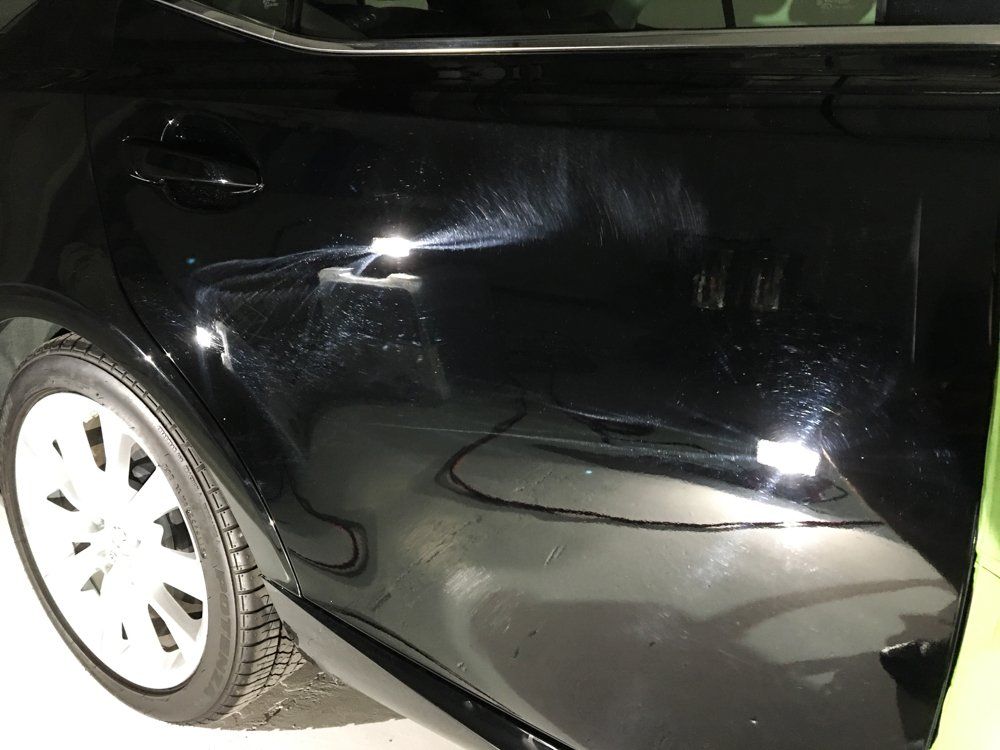 Black car door with water marks and reflections.