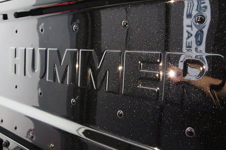 Close-up of a black Hummer emblem on a sparkly black surface, with silver rivets.