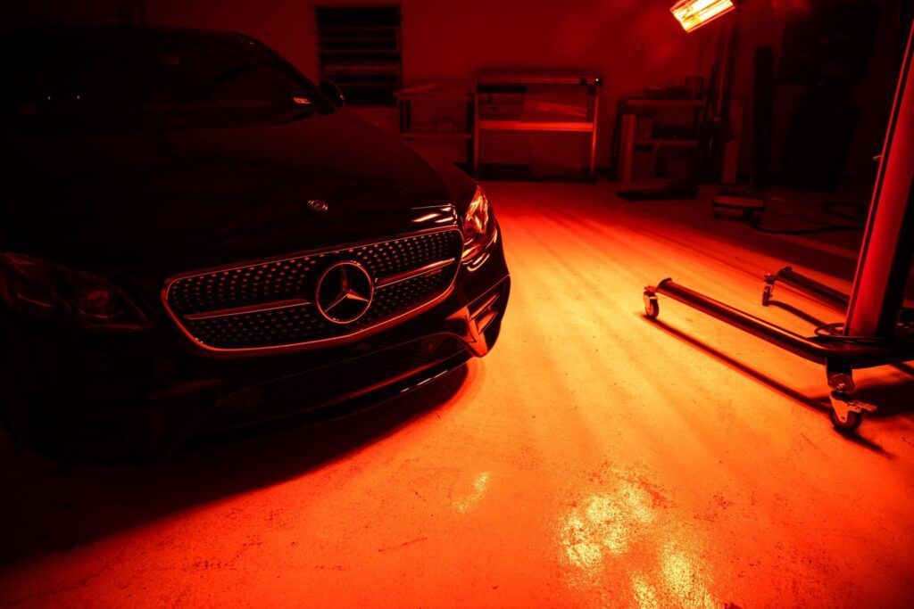 Black Mercedes in a garage, illuminated by red light.