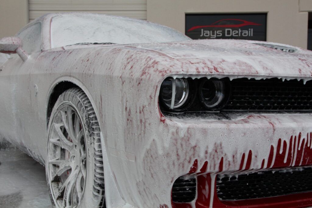 Red car covered in white foam at Jays Detail.