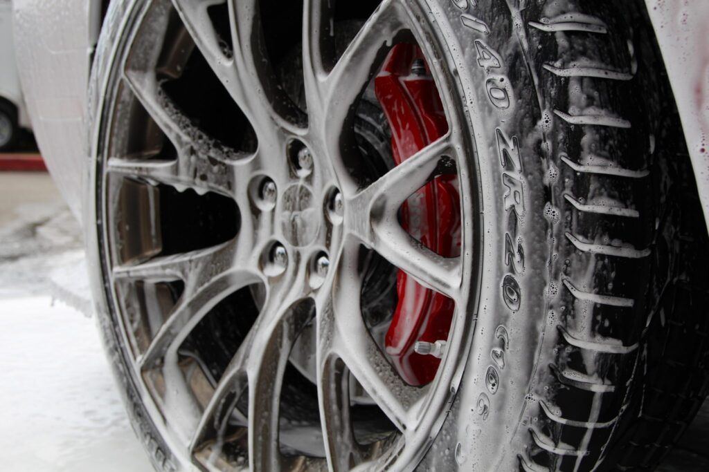 Car wheel with foam cleaning the tire and red brake.
