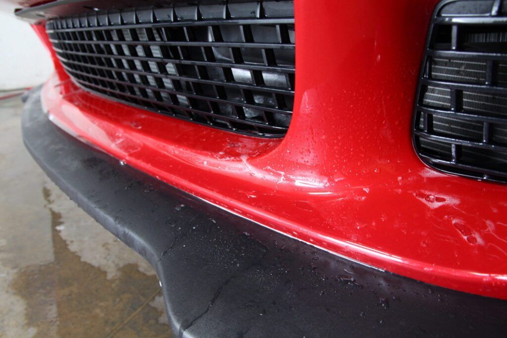 Red Dodge Challenger's close-up view. Grille, SRT emblem, and headlights are visible.