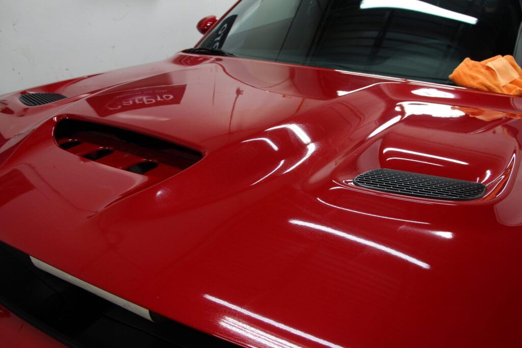 Red car hood with dual air vents; shiny, reflecting lights.