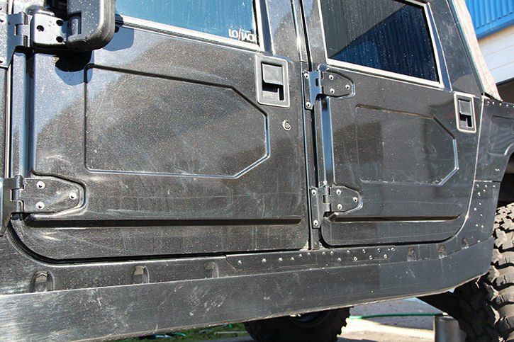 Black Hummer door detail, with visible hinges, handles, and riveted lower panel.