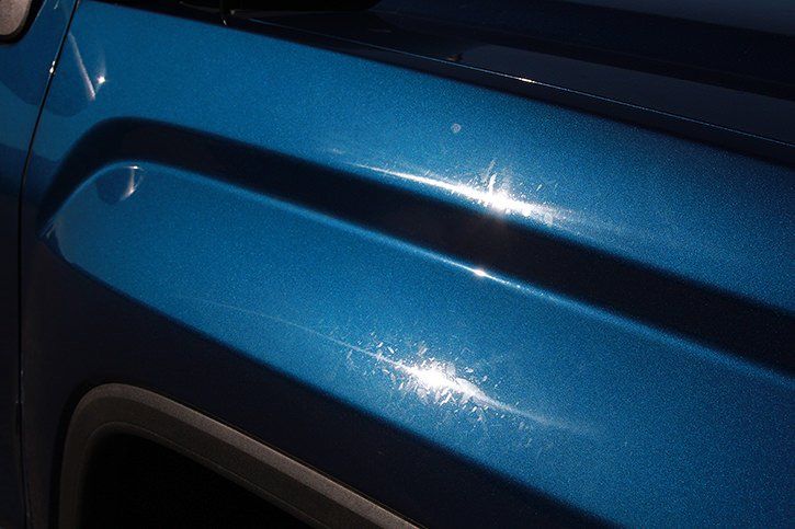 Blue metallic car fender reflecting sunlight.