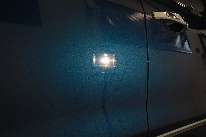 Blue car door with a bright, square light shining on it.