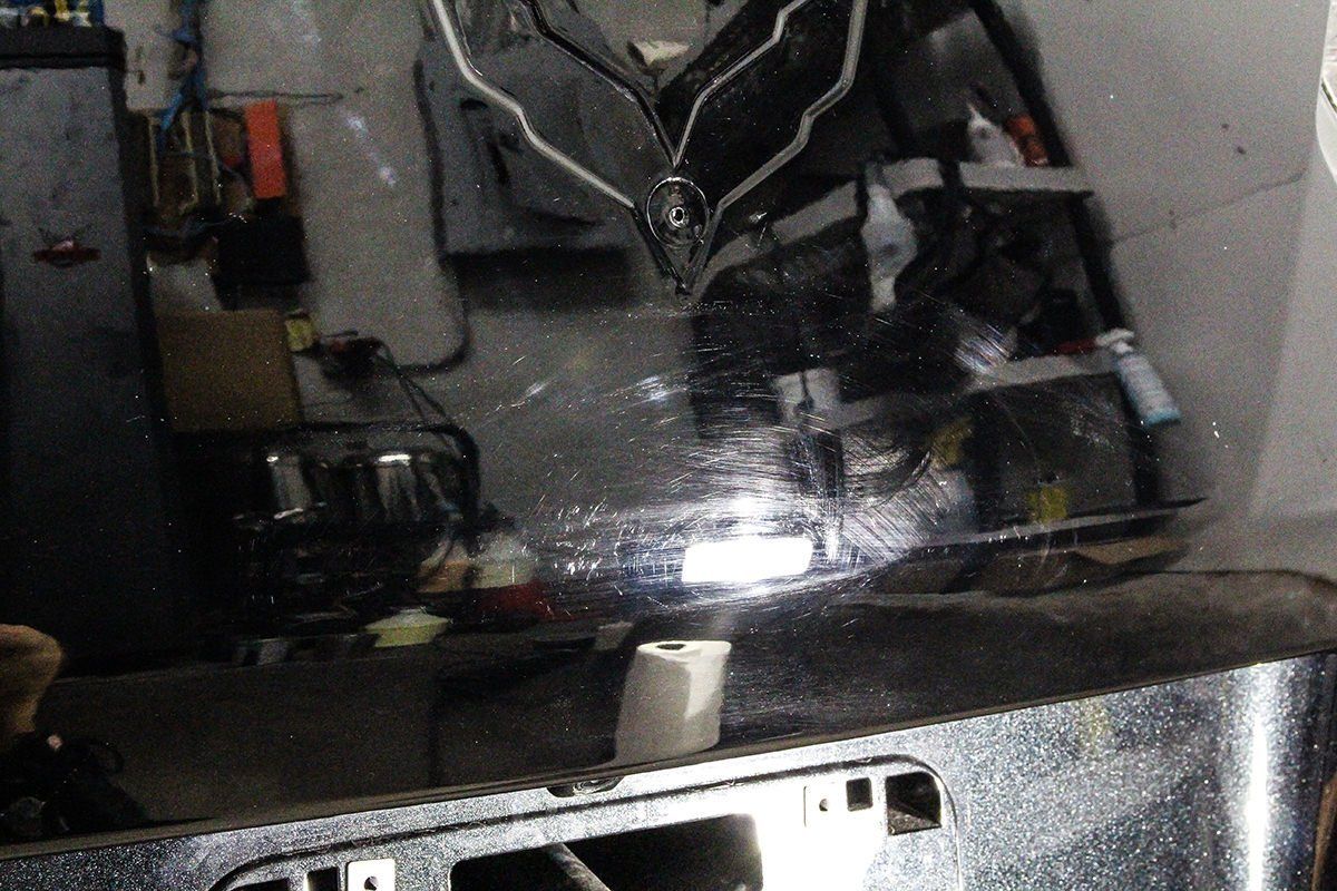 Close-up of a shiny, reflective surface. Objects and a cluttered space are reflected.