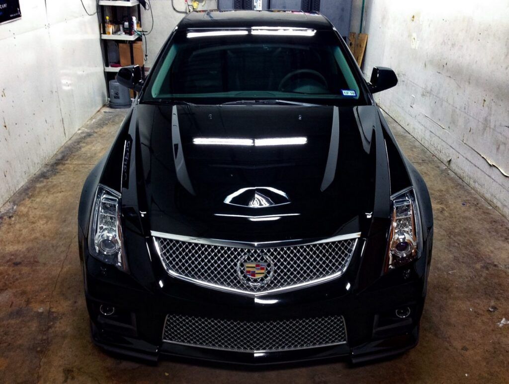 Black Cadillac CTS-V, front view, inside garage. The car is shiny, with a light bar on the roof.