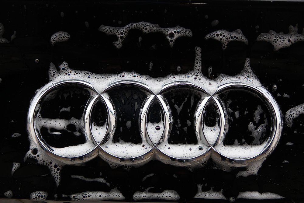 Audi logo covered in soapy foam, black background.