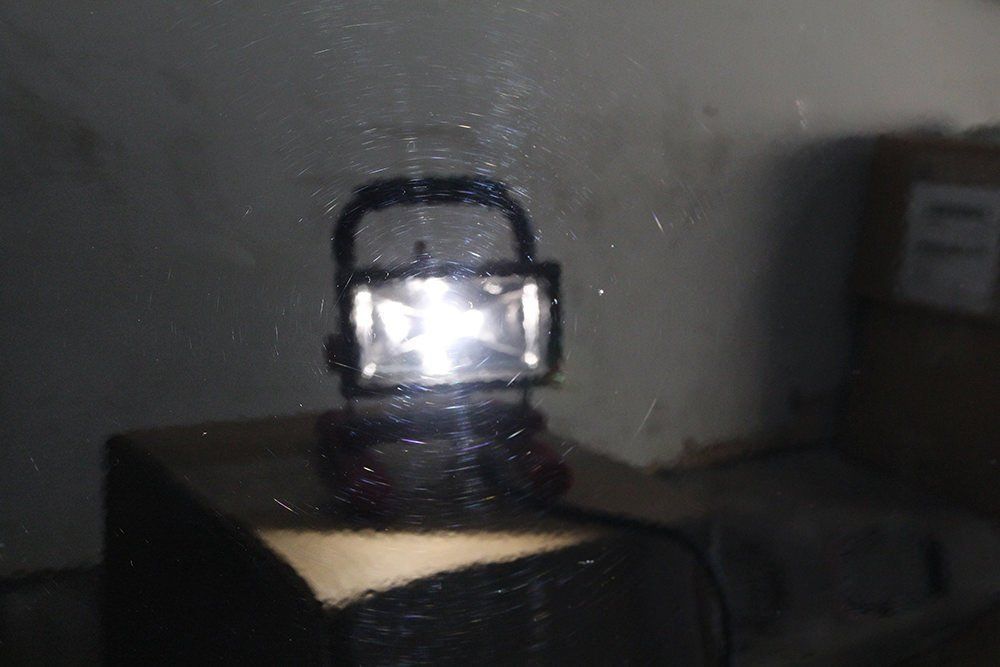 Bright work light on a small table, illuminating a dark, possibly industrial, space.