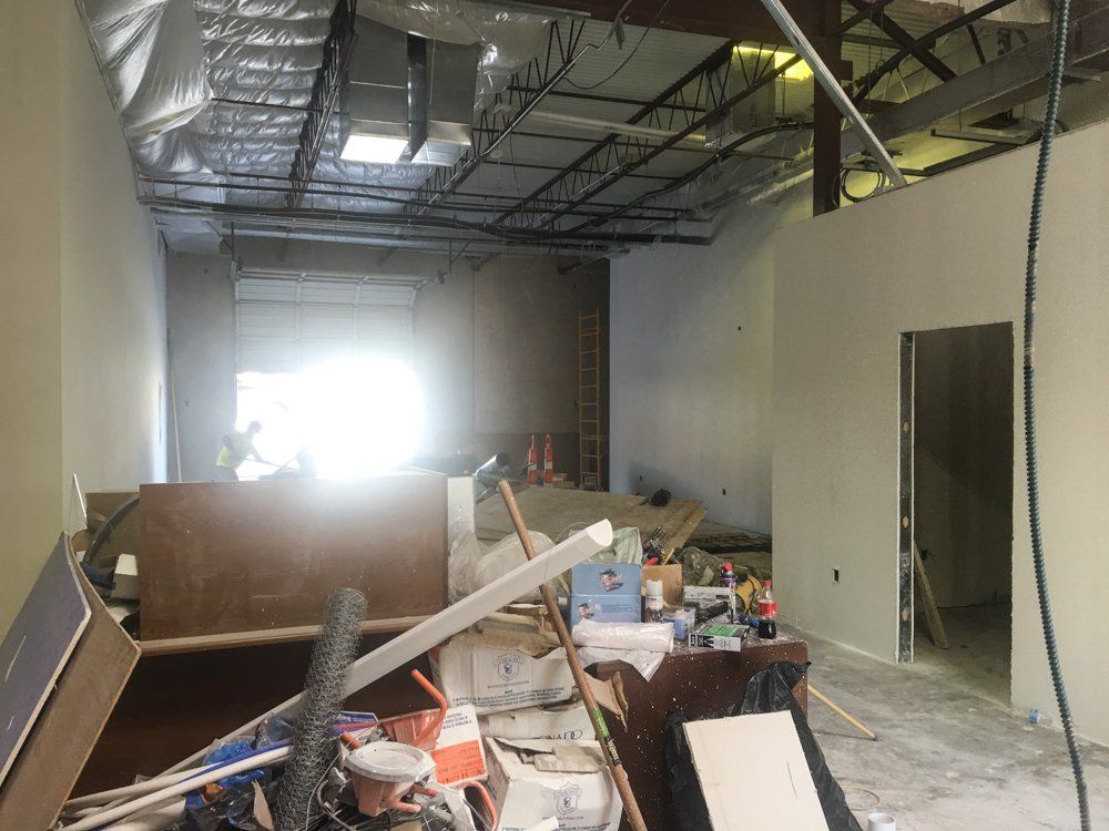 Construction site interior. Debris in the foreground, unfinished walls, bright light from a doorway.