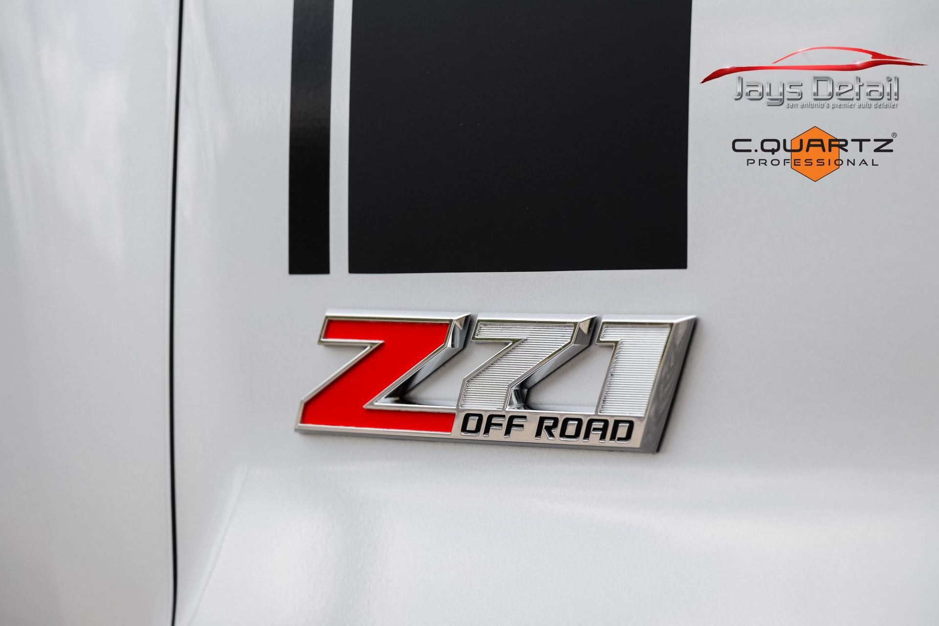 Silver Z71 Off Road emblem with red accents on a white vehicle with black stripes.