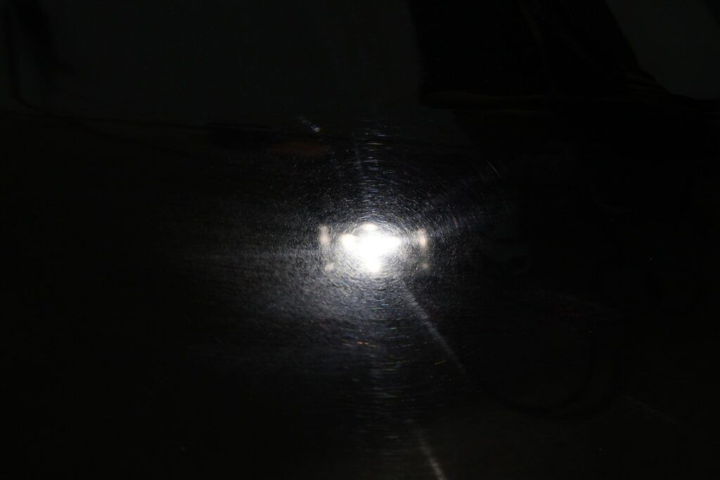 Blue metallic car fender reflecting sunlight.