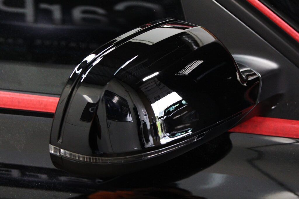 Black glossy car side mirror, red stripe visible.