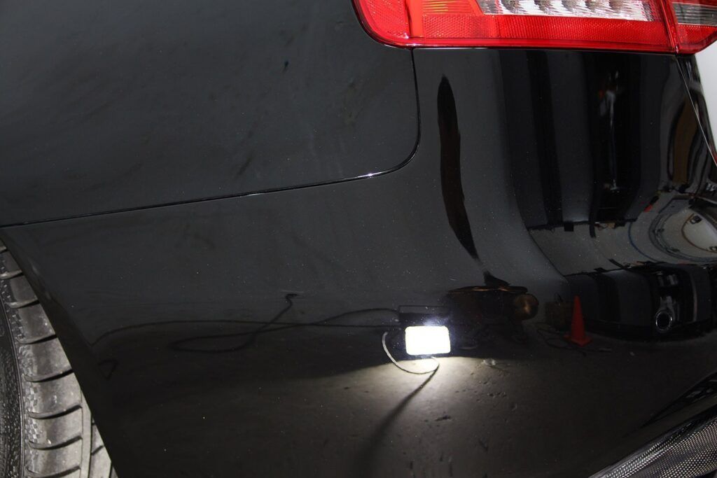 A black car with a spotlight shining on the ground.