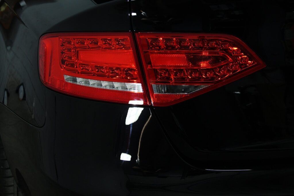 Black car's red taillight, with multiple LED lights, illuminated.