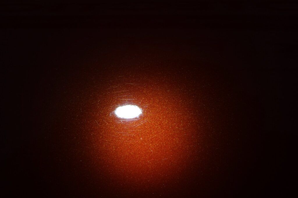 Bright white oval glow on a textured orange-brown surface; soft gradient background.