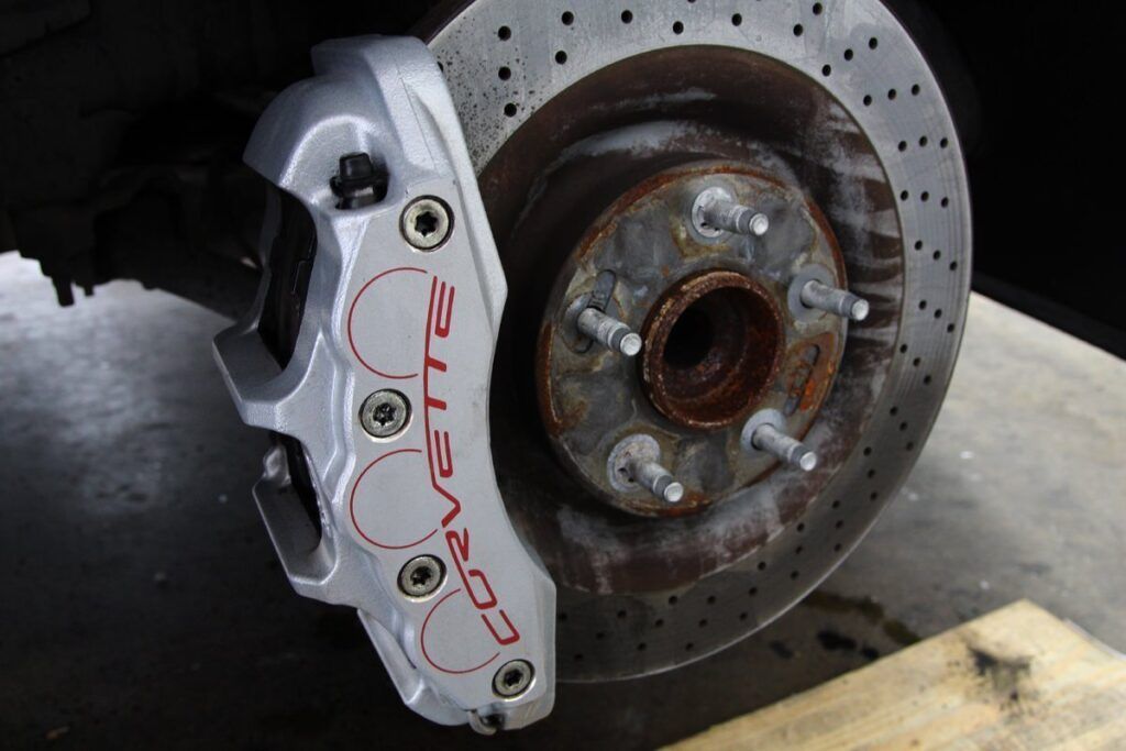 Silver Corvette brake caliper with red lettering and drilled rotor.