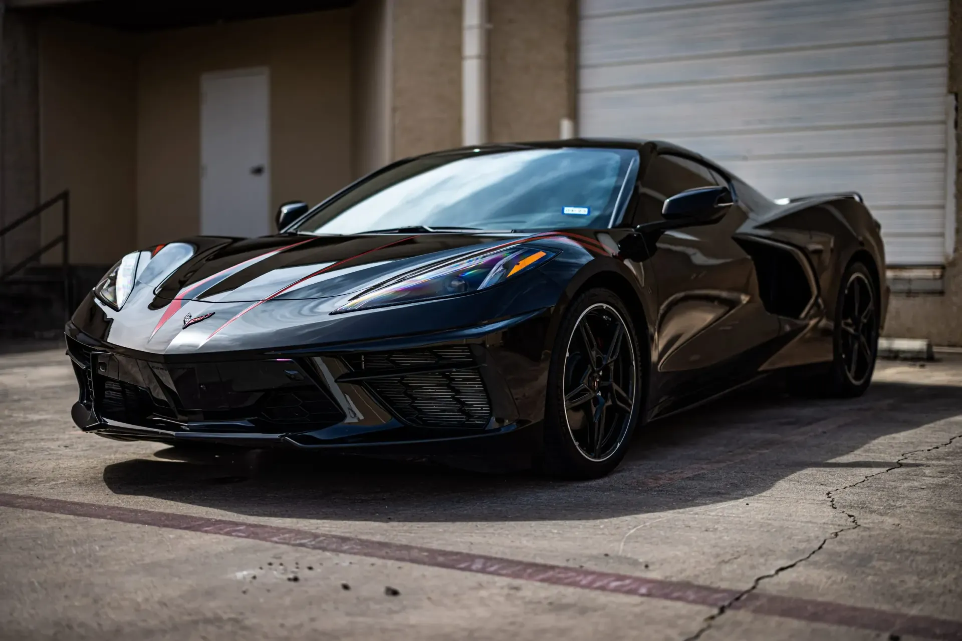 Black Chevrolet Corvette parked outside, front angled shot.