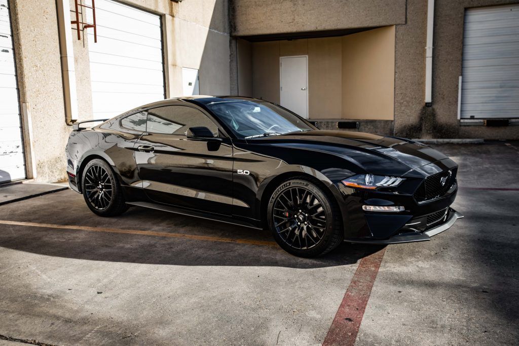 Black Mustang coupe parked in a concrete garage.