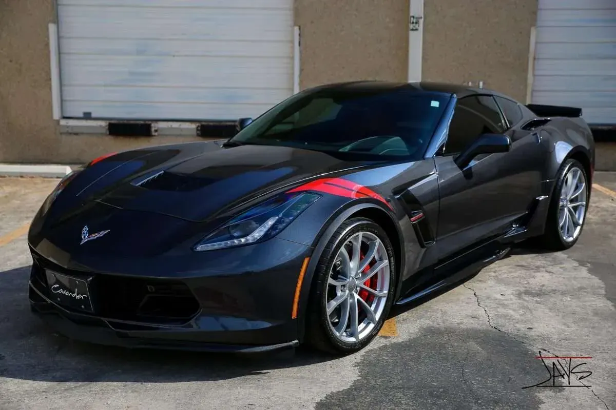 Dark gray Corvette sports car with red accent stripes, parked in front of a building.