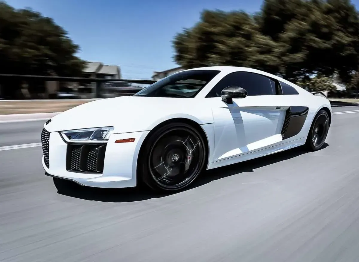 White Audi R8 sports car speeding on a road, black wheels, motion blur.