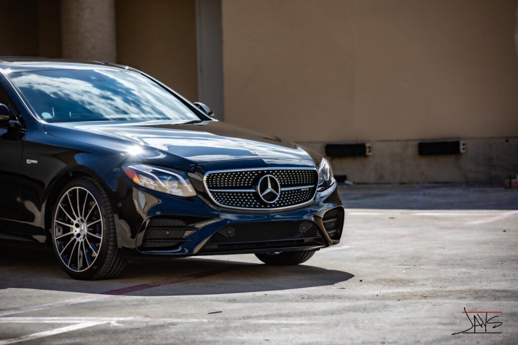 Black Mercedes-Benz car parked near a building on a sunny day.