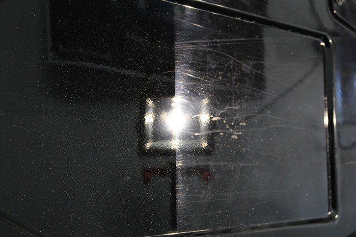Black car surface: half polished, half scratched.