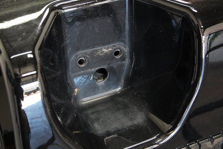 Black car door handle cavity with three holes.
