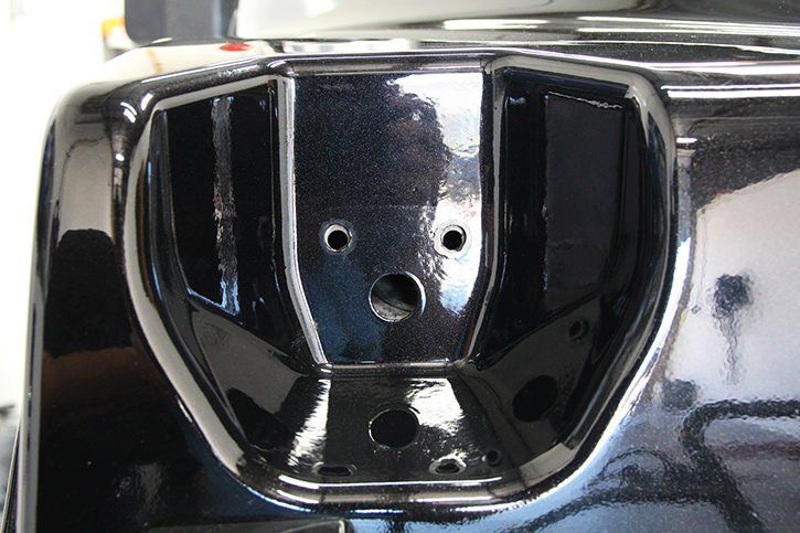 Black vehicle bumper detail with recessed areas and holes.