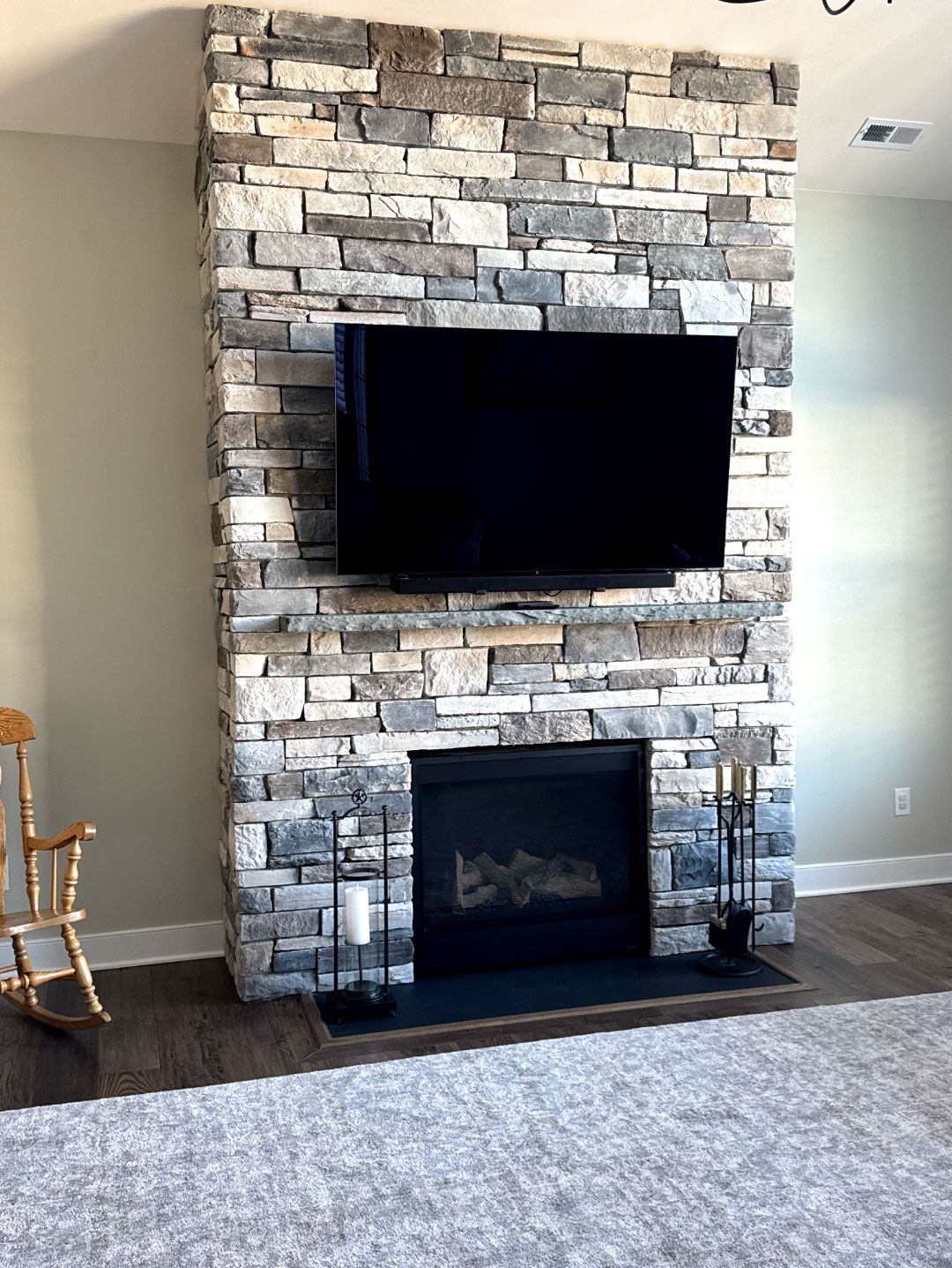 A living room with a fireplace and a flat screen tv mounted on the wall.