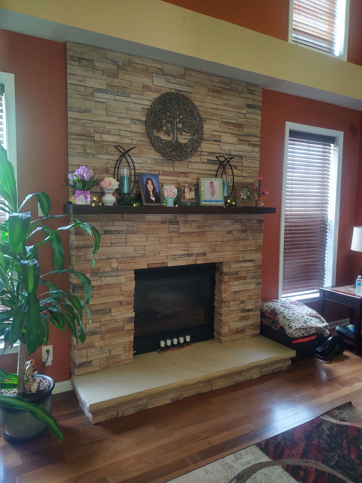 A living room with a fireplace and a shelf with pictures on it.