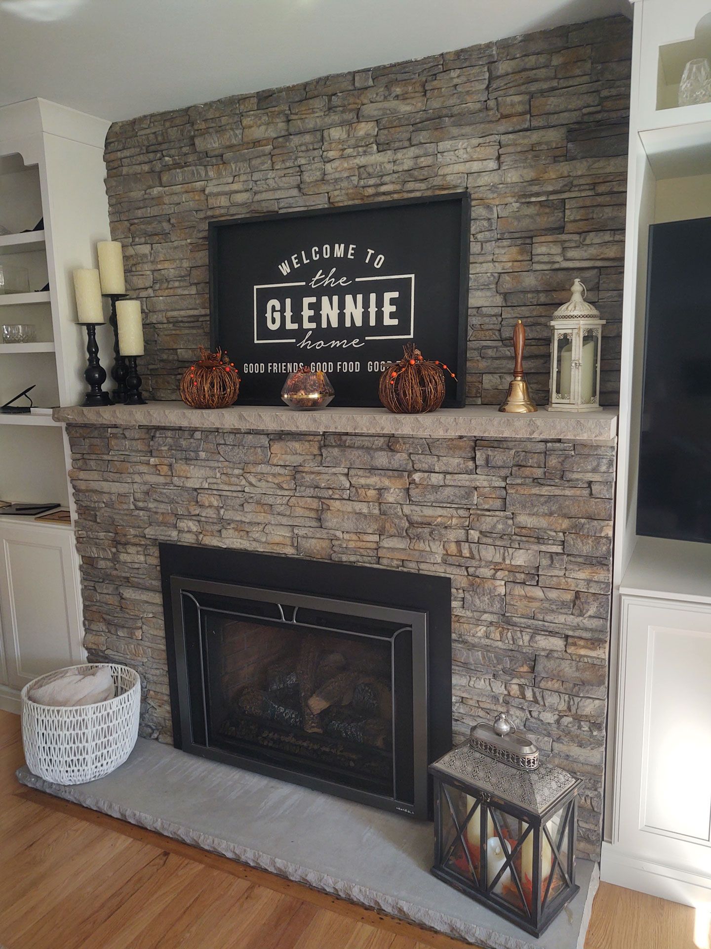 A living room with a fireplace and a sign that says welcome to the glennie home