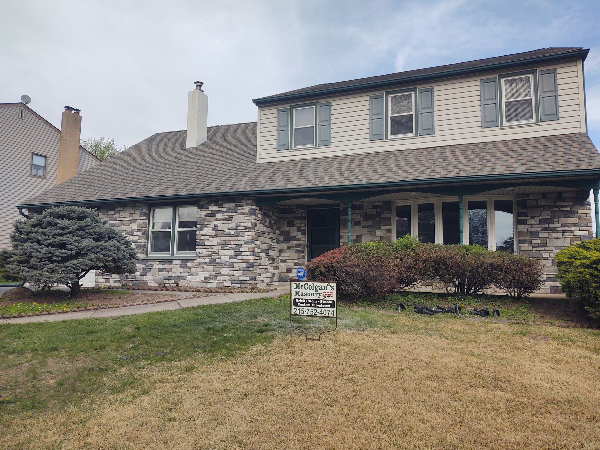 A large brick house with a roof and a sign in front of it.