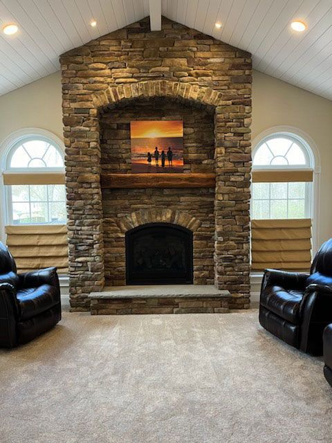 A living room with two chairs and a stone fireplace