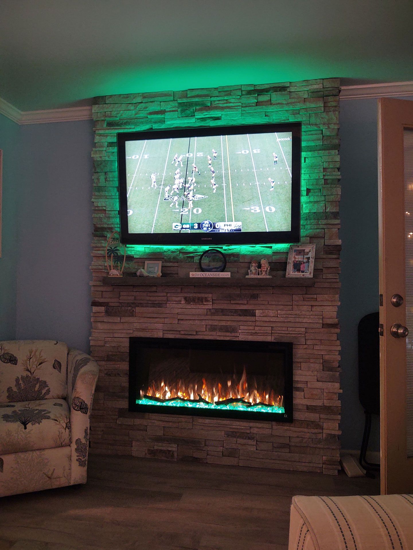 A living room with a fireplace and a flat screen tv with green lights.