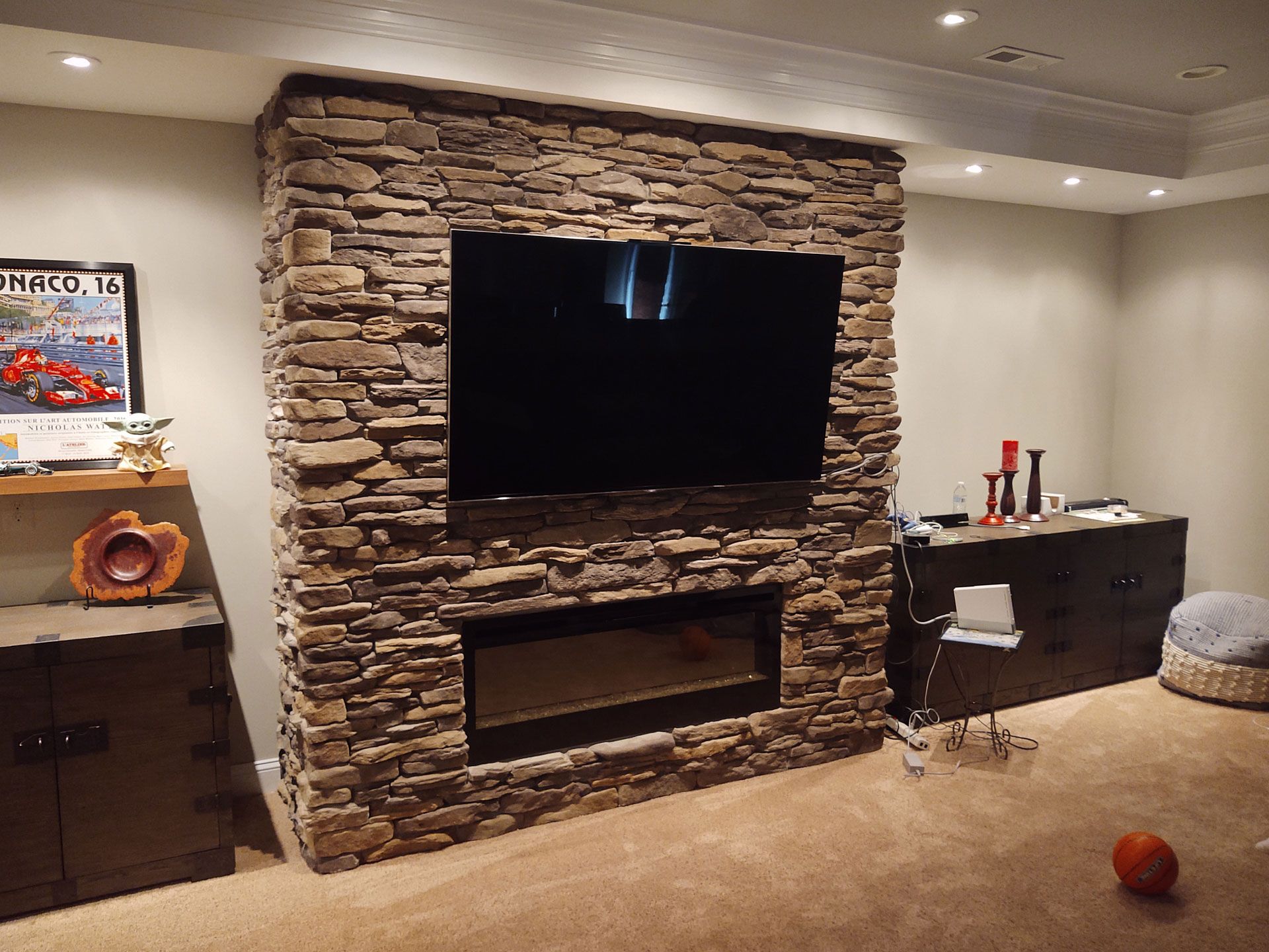 A living room with a stone fireplace and a flat screen tv.