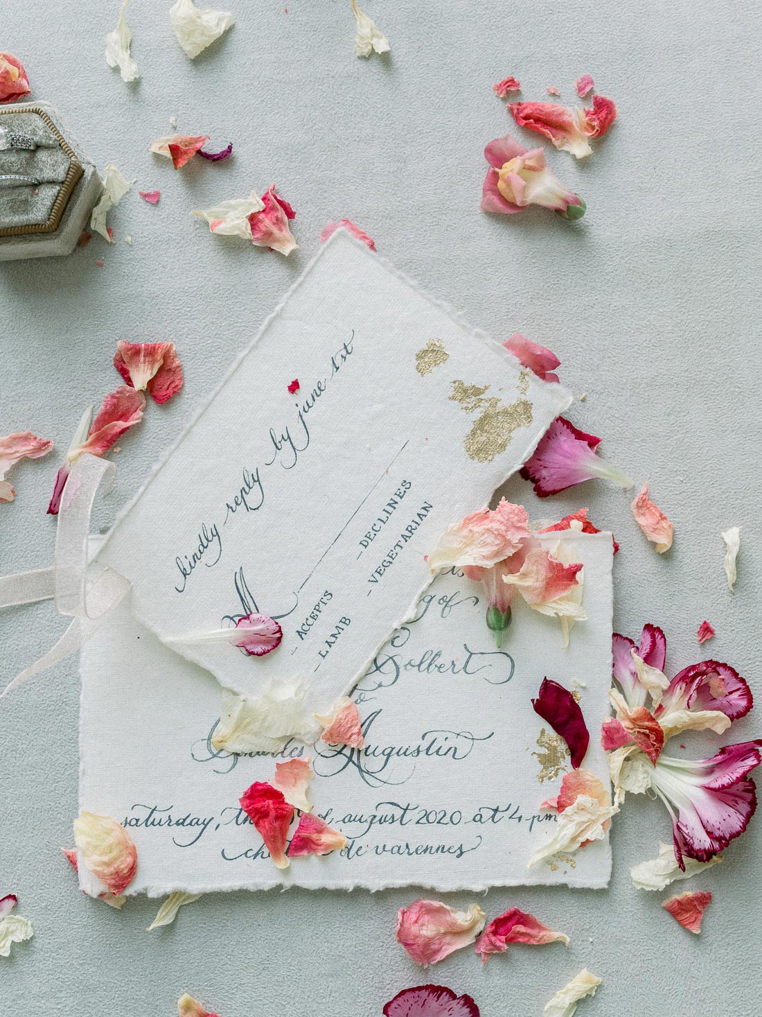Papeterie de mariage avec pétales séchés roses et crème dispersés autour